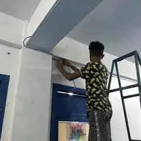 A technician on a ladder running network cable along a school wall