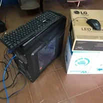 A computer tower and keyboard beside a monitor box