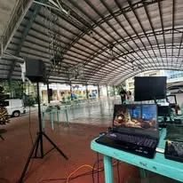 A speaker on a stand and a laptop on a table under a covered court